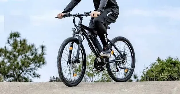 Un cycliste franchit une crête de terre sur le VTT électrique Touroll U1, ciel dégagé